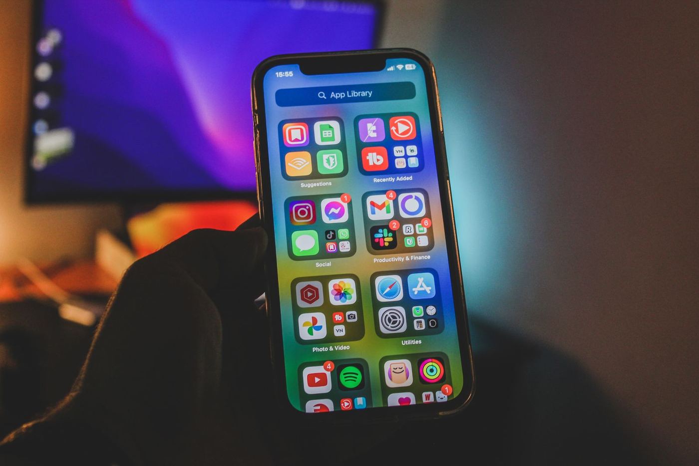 A hand scrolling a phone home screen in low light